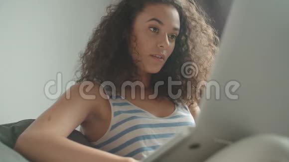 漂亮的女人在客厅里用笔记本电脑在沙发上放松视频的预览图