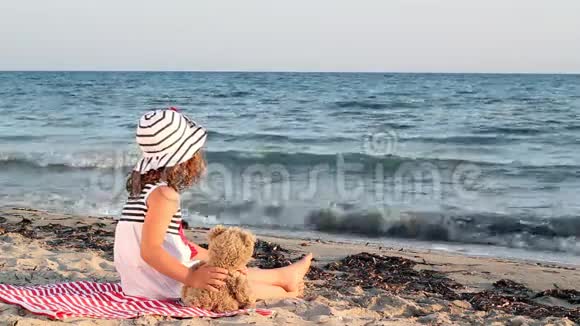 带着玩具熊的小女孩在海滩上视频的预览图