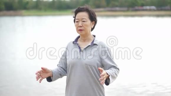 亚洲长者练习太池齐公在湖边户外运动视频的预览图
