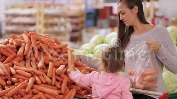 母亲和女儿在超市购物时选择蔬菜视频的预览图