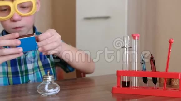 家庭化学实验男孩在燃烧的酒精灯上用红色液体加热试管视频的预览图