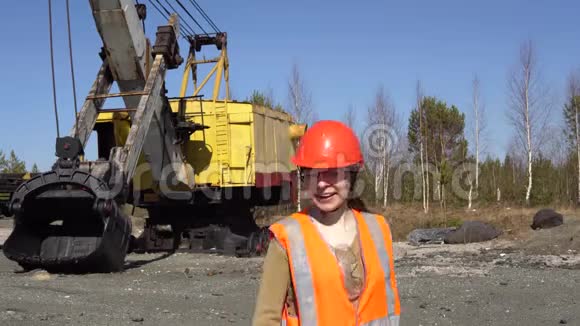 一名年轻的女工站在挖掘机旁视频的预览图