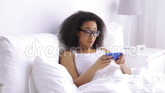 非洲女人在家里的床上打电话给智能手机视频的预览图