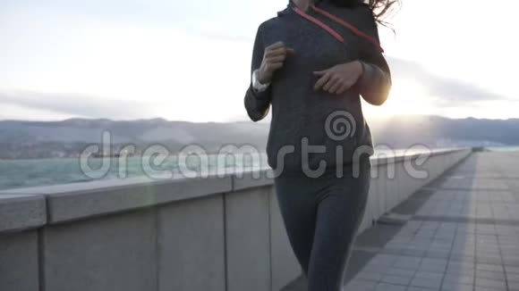 穿着帽衫在海滨城市慢跑的年轻女子视频的预览图