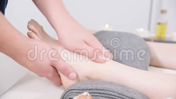 一名男性理疗师在美容和健康水疗中心为一名年轻女孩做足底按摩足部和身体护理视频的预览图
