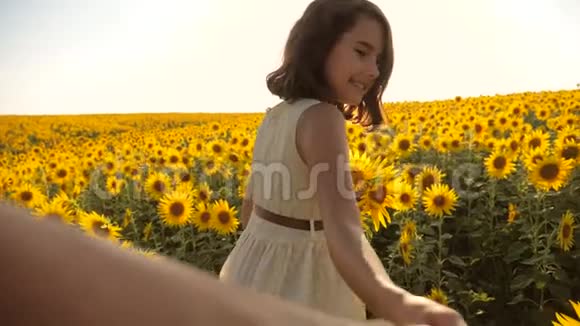 爸爸和女儿沿着田野走着夕阳下向日葵牵着手第一人称的景色慢速视频视频的预览图
