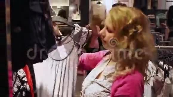 一位年轻的金发女郎在店里试衣服视频的预览图