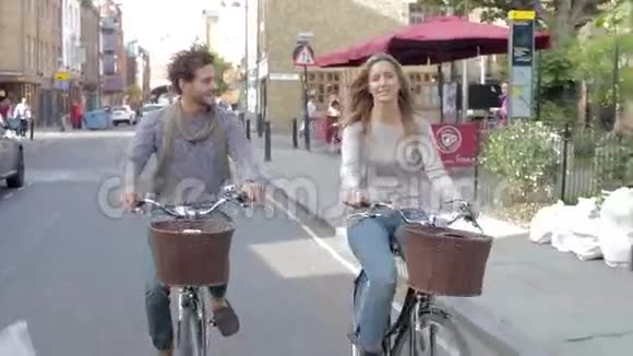 一对夫妇一起骑自行车沿着城市街道视频的预览图
