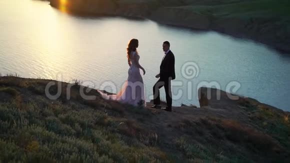 新郎新娘日落时分在山上散步视频的预览图