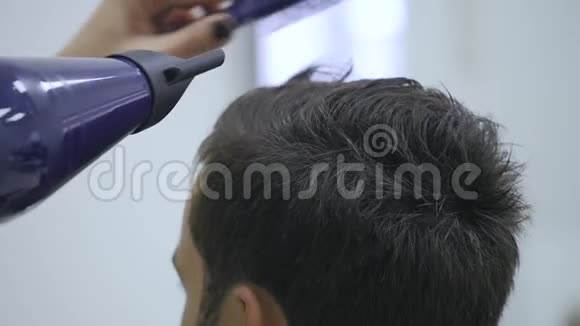专业美发店烘干头发男青年顾客和女理发师视频的预览图