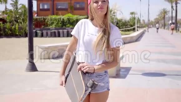 年轻女子边走边拿滑板视频的预览图