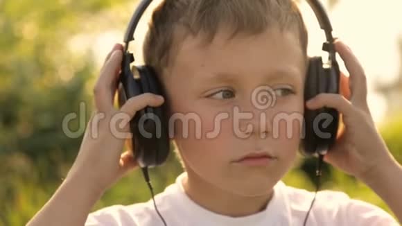 在夕阳下男孩通过耳机听音乐视频的预览图