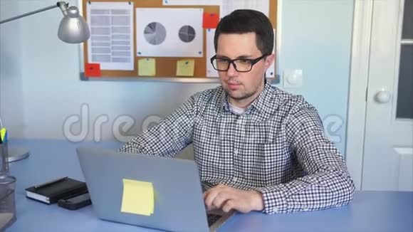 年轻人坐在办公室的桌子上用笔记本电脑工作视频的预览图