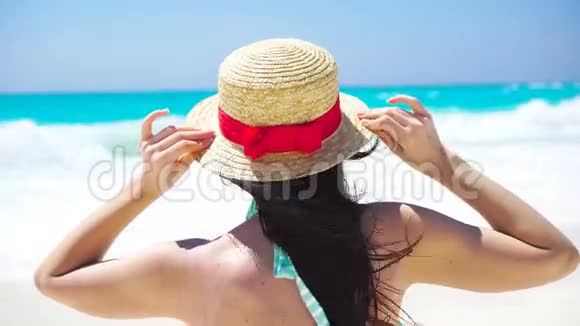 在白色海滩上的暑假戴帽子的美女的背面景色视频的预览图
