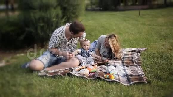 美丽的父母爸爸妈妈在公园野餐玩得开心视频的预览图