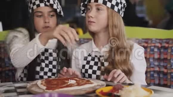 穿着制服的快乐女孩在咖啡馆的主班上做披萨4K视频的预览图