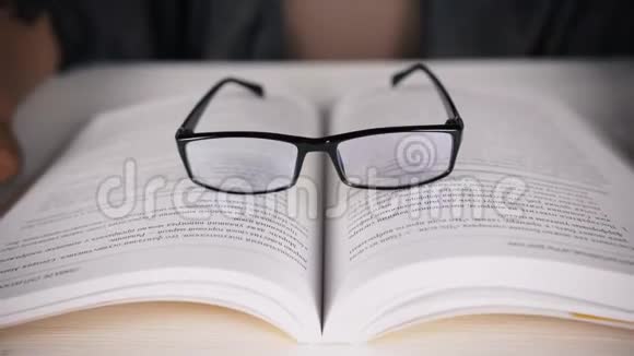 女孩坐在一张白色的桌子上戴着眼镜看着一本书日记视力不好视频的预览图