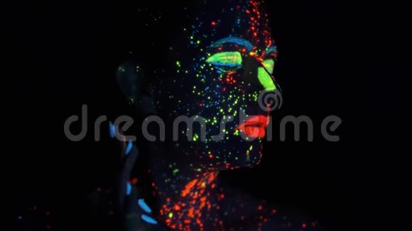 油漆在紫外线下发光一个画着发光颜料的女孩的肖像视频的预览图