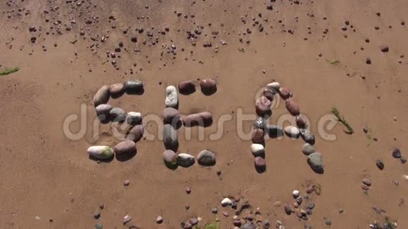用湿石和海浪写在沙子上的海字视频的预览图
