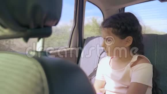 伤心的女孩无聊地坐在车里后座旅行小女孩在车里无聊概念概念长途旅行视频的预览图