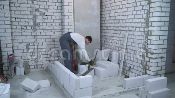 男建筑工人铺设加气混凝土砌块并用气泡水平检查视频的预览图