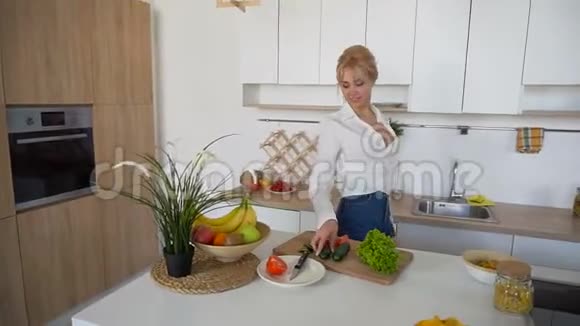 漂亮的女孩在现代厨房的砧板上准备新鲜蔬菜沙拉视频的预览图