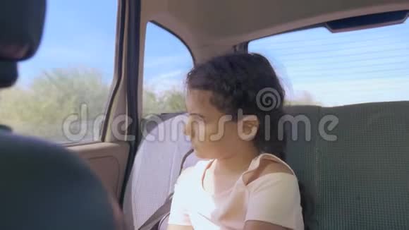 伤心的女孩无聊地坐在车里后座旅行小女孩在车里无聊运动概念长途旅行视频的预览图