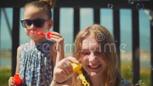 幸福微笑的家人姐妹们都在玩耍在夏天的户外吹肥皂泡库存录像视频的预览图