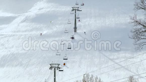人们在冬季滑雪场的雪坡上滑雪和滑雪板雪山上的滑雪电梯冬季滑雪活动视频的预览图