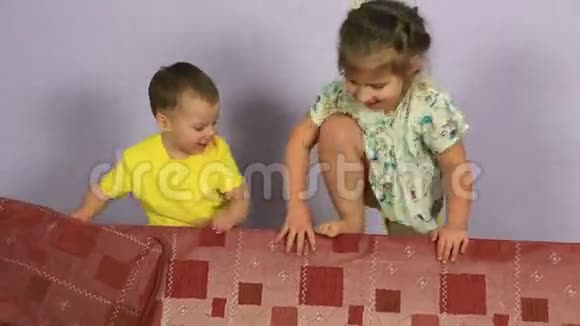 快乐快乐的弟弟妹妹在沙发上玩耍和跳跃视频的预览图