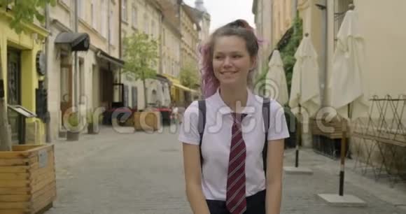 年轻漂亮的学生女孩背着背包走路微笑着视频的预览图