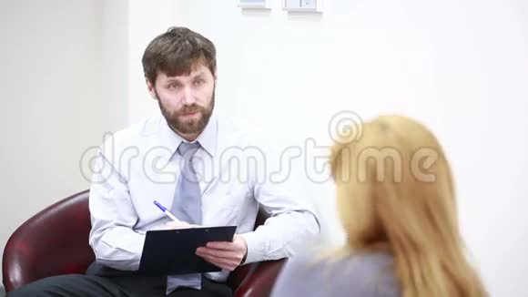 一位漂亮的男性心理医生在她探视期间看着病人视频的预览图