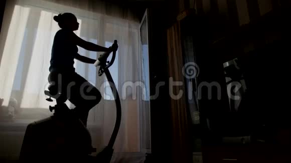 在家里骑着固定自行车锻炼的女人视频的预览图