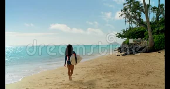 女性冲浪者在海滩上用冲浪板行走4k视频的预览图
