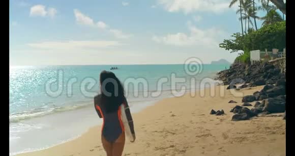女性冲浪者在海滩上用冲浪板行走4k视频的预览图