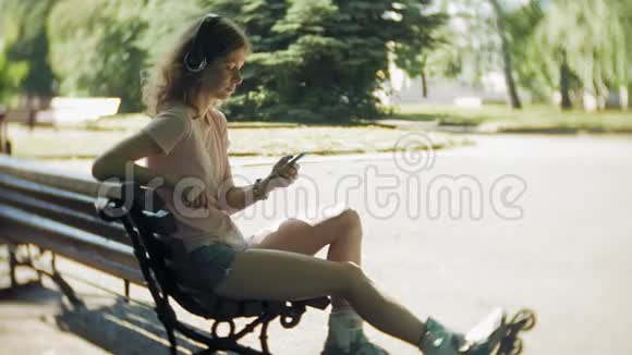 女子滑旱冰和听音乐耳机电话在公园视频的预览图