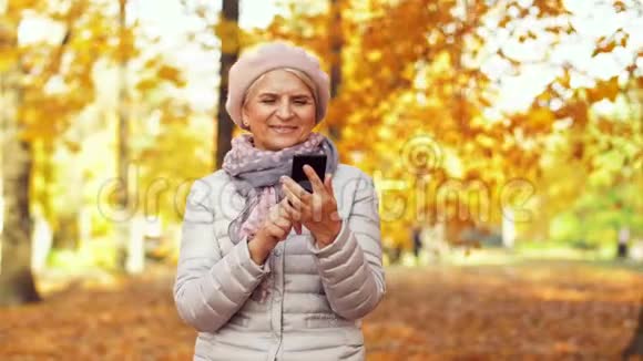 秋天公园有智能手机的快乐高级女人视频的预览图