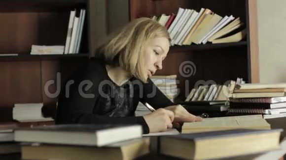 女学生坐在书桌前从书中写出必要的信息视频的预览图