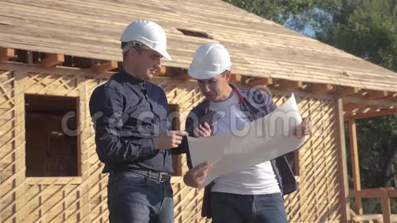 团队合作概念建设构建建筑师慢动作视频两名戴头盔的建筑工人研究数字平板电脑视频的预览图