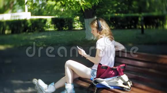 女子滑旱冰和听音乐耳机电话在公园视频的预览图