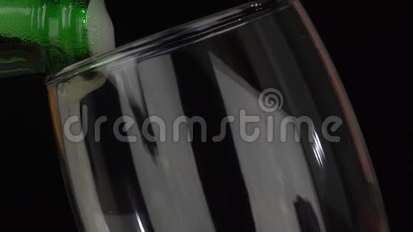 黑色背景下新鲜啤酒从瓶子倒入玻璃的细节视频的预览图