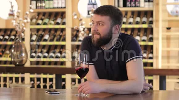 一个孤独的人拿着一杯红酒一个年轻的人拿着一杯红酒一个男人在一家餐馆喝红酒视频的预览图