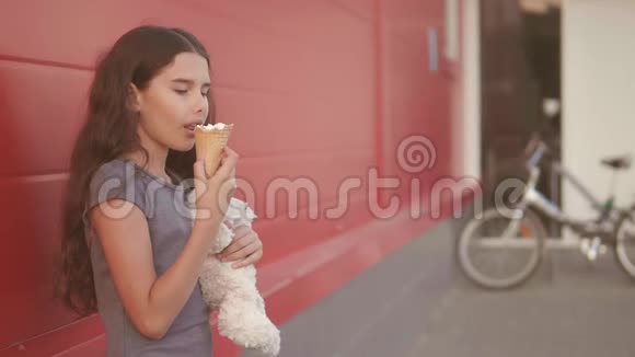 小女孩在街上吃冰淇淋有一个软玩具动作慢动作视频女孩的生活方式和冰淇淋视频的预览图