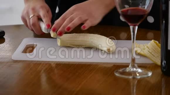 女人在家庭厨房的木制厨房板上切香蕉在家做饭厨房里的家庭气氛视频的预览图