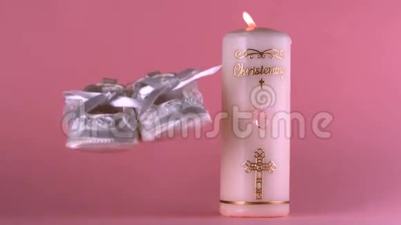 婴儿鞋在点燃的洗礼蜡烛旁视频的预览图