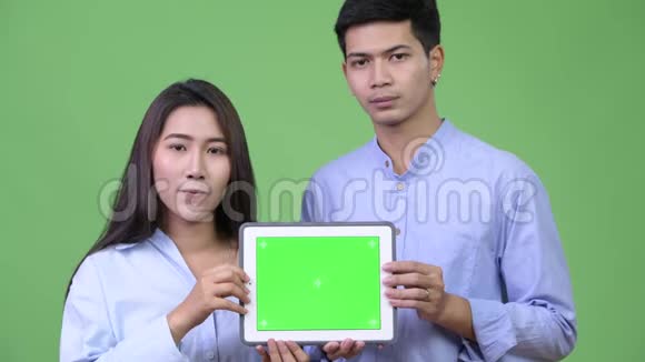 年轻的亚洲商界夫妇一起展示数码平板电脑视频的预览图