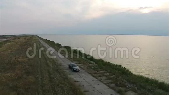 无人机上的摄像机跟踪着汽车它沿着靠近大海的堤岸行驶视频的预览图