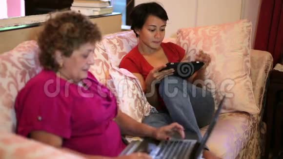 母亲和女儿在家里一起使用平板电脑视频的预览图