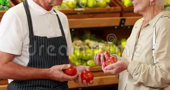 高级顾客和工人讨论杂货店的蔬菜视频的预览图