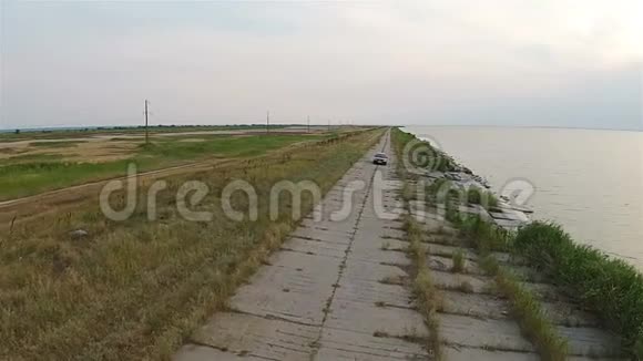 无人机上的摄像机跟踪着汽车它沿着靠近大海的堤岸行驶视频的预览图